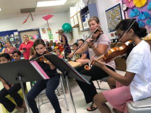 Two girls and a woman playing violin for the incoming graduates