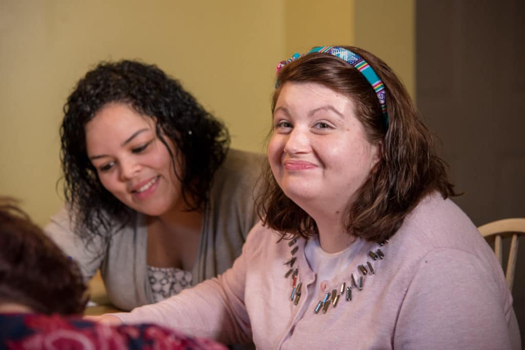 Woman smiling with another woman in backgroud